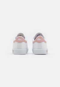 White leather sneakers with pink accents at the heel, textured paneling, and a white rubber sole. Lacoste logo embroidered on the back.
