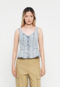 Lichtgewassen denim peplumtop met een V-hals, knoopsluiting en subtiele stikdetails. Glad textuur met een uitlopende zoom.