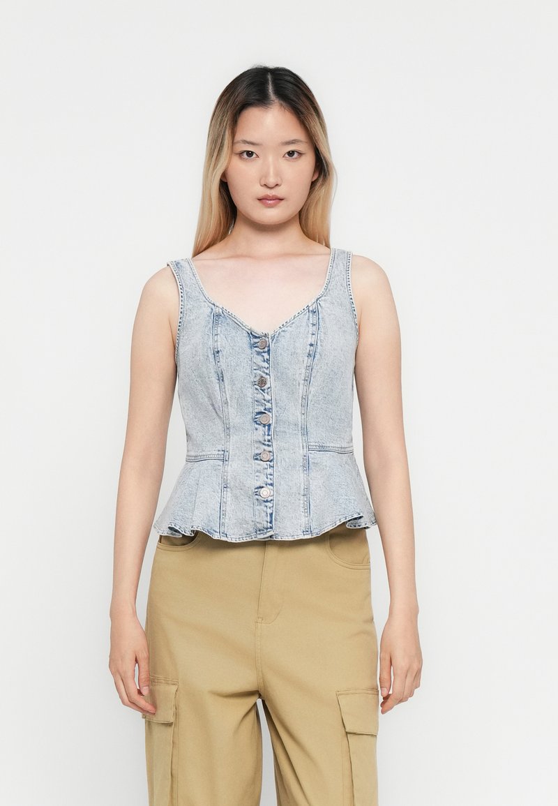 Lichtgewassen denim peplumtop met een V-hals, knoopsluiting en subtiele stikdetails. Glad textuur met een uitlopende zoom.