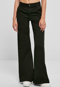 Svarta vida byxor i bomull med en slät yta. Har en knappstängning och framfickor; sitter i midjan.