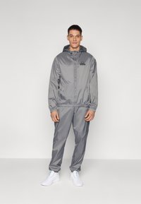 Lightweight, gray hooded jacket and matching pants made of smooth, shiny fabric. Features elastic cuffs and a small logo on the chest.
