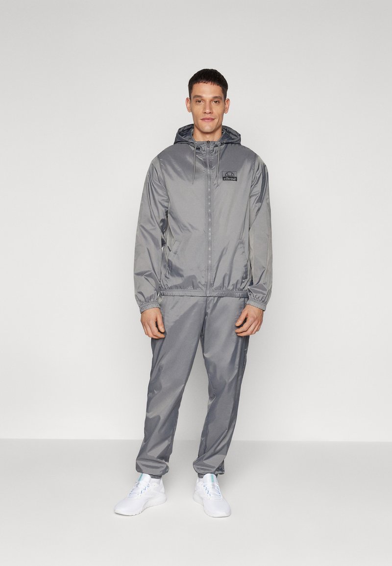 Lightweight, gray hooded jacket and matching pants made of smooth, shiny fabric. Features elastic cuffs and a small logo on the chest.