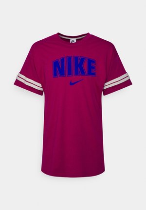T-shirt Nike magenta à manches courtes avec le texte bleu "NIKE" et le swoosh sur le devant, avec des rayures blanches sur chaque manche.
