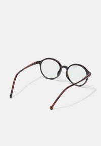 Okrągłe okulary w kolorze tortoise z przezroczystymi soczewkami, o błyszczącej powierzchni i smukłych zausznikach, które elegancko zwężają się ku końcom.