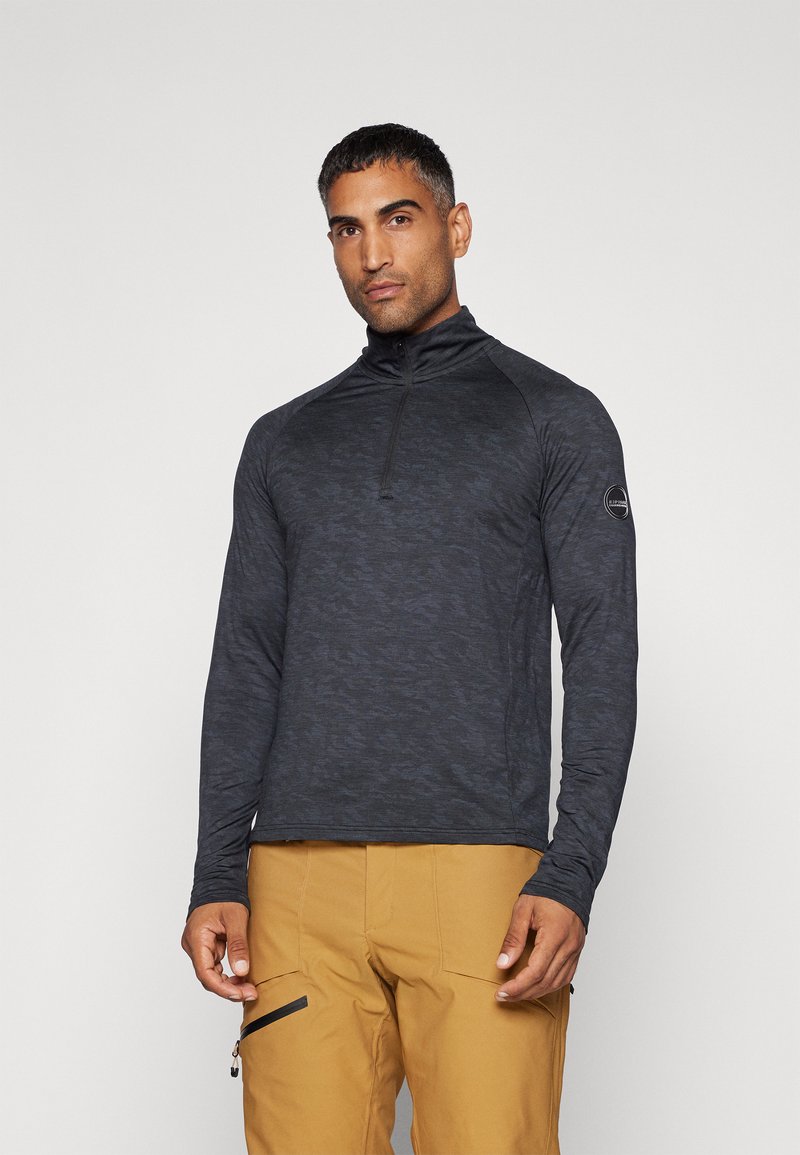 Top de manga larga gris oscuro con cuello con cremallera, que presenta un patrón texturizado y un diseño ajustado. Incluye un acento de logo cerca de la manga izquierda.