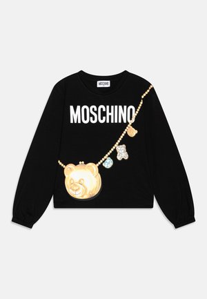 Czarny longsleeve z napisem "MOSCHINO" w białym kolorze, ozdobiony złotym wisiorkiem w kształcie misia i kolorowymi zawieszkami wzdłuż łańcucha.