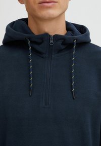Navy fleece hoodie with a half-zip design, featuring a drawstring hood with yellow accents and a soft, textured fabric.