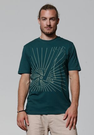 Teal t-shirt met een grafisch ontwerp van een fietswiel en stralen in een crèmekleur. Gemaakt van zachte, rekbare stof met korte mouwen.