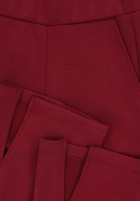 Bordeaux stretchbroek met een gladde textuur, voorzien van een platte tailleband, twee zijzakken en nette stiksels langs de randen.