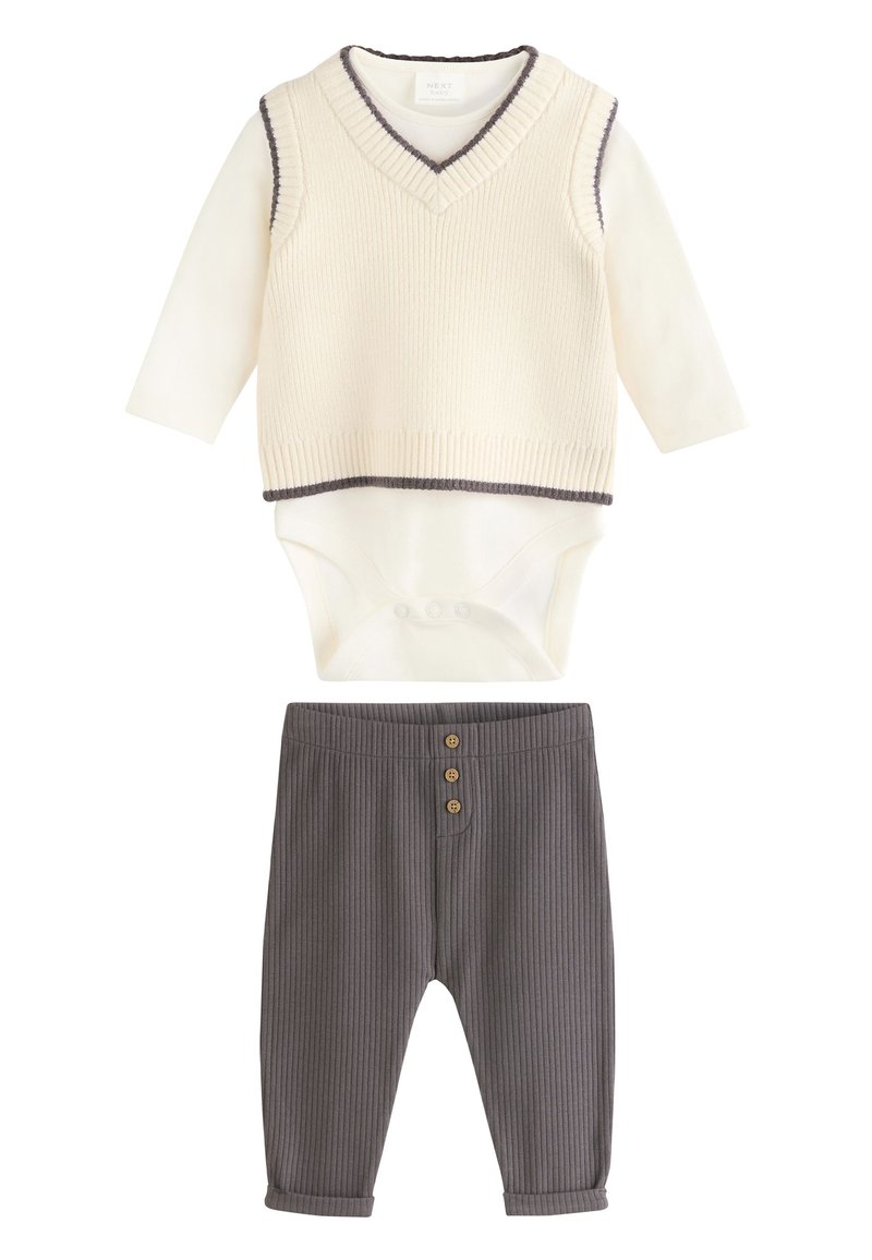 Cream ribbed vest with dark trim over long-sleeve bodysuit, paired with gray ribbed pants featuring three button accents.