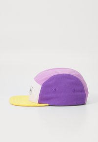 Bunte Baseballmütze mit einem gelben Schild, lila und lavendelfarbenen Paneelen sowie einer weißen Vorderseite mit einem Logo-Patch. Strukturierter Stoff, strukturierte Passform.