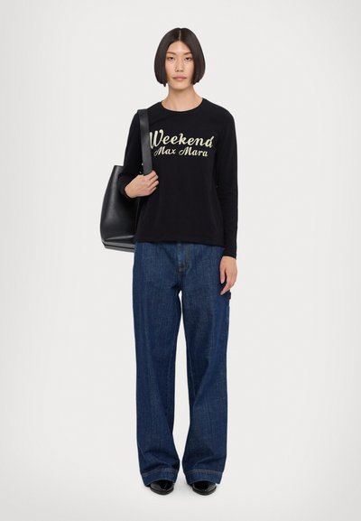 Svart langermet skjorte med gyllen tekst "Weekend Max Mara", kombinert med løse blå denimjeans og en svart tote bag. Flade svarte sko.