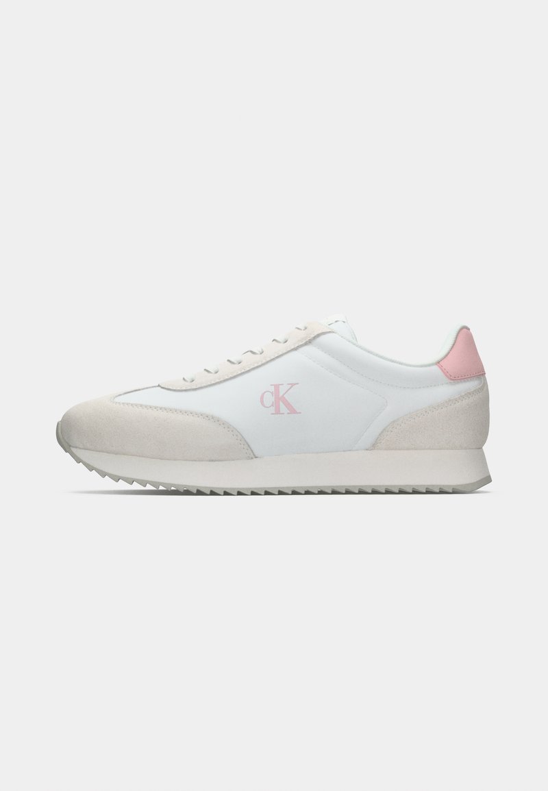 Des chaussures de sport avec une tige synthétique blanche, des accents en suède gris, un talon rose clair et une semelle en caoutchouc texturée avec un motif en zigzag.