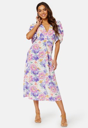 Robe midi florale blanche, avec des motifs violets, roses et oranges. Manches bouffantes et décolleté en V, fabriquée en tissu léger.