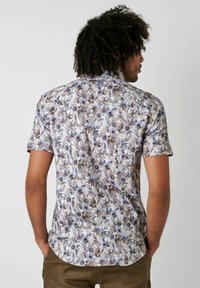 Kurzarmhemd aus leichtem Stoff mit floralem Muster in Blau- und Brauntönen; abgerundetem Saum und Kragen, mit entspannter Passform.