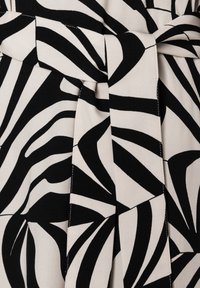 Schwarz-weiß gemusteter Stoff mit kräftigen, wellenförmigen Streifen. Glatte Textur mit einem Taillendetail und kontrastierenden Farben.