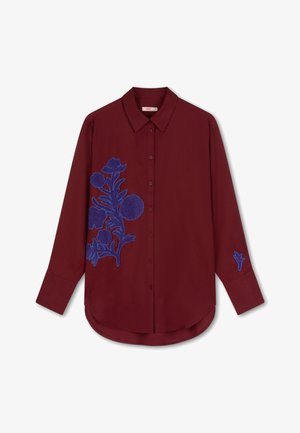 Bordeaux overhemd met lange mouwen, voorzien van blauwe bloemenborduursel aan de voorkant en op de mouwen. Gladde stof en een afgeronde zoom.