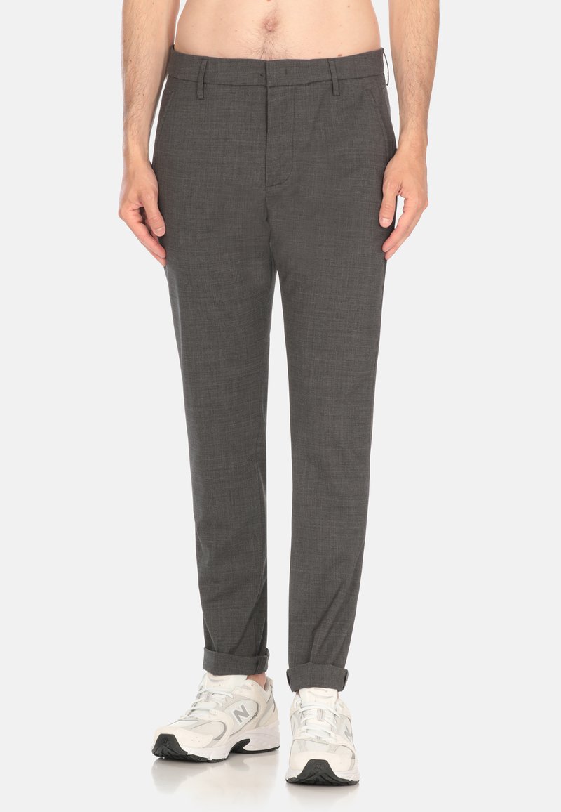 Pantaloni grigi su misura con una fine trama, dotati di fronte piatto, tasche laterali e orli arrotolati, abbinati a scarpe da ginnastica bianche.