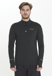 Zwarte langarm pullover met hoge kraag en halve ritssluiting. Bevat een gestructureerde stof en een klein wit logo op de borst, plus stipaccenten op de mouwen.