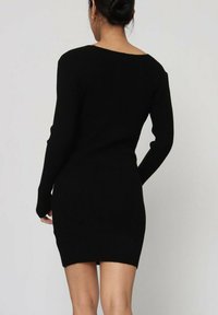 Robe noire en tricot côtelé avec des manches longues, silhouette ajustée et décolleté arrondi. Design minimaliste avec une texture lisse.