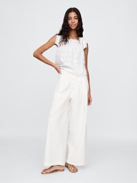 Hvit brodert topp med scalloped ermer, parret med vide hvite bukser og flate sandaler. Enkel og lett stoff.