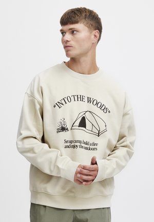 Beige sweatshirt with a round neckline, featuring a campfire and tent graphic print. Has ribbed cuffs and hem, made from soft cotton blend fabric.