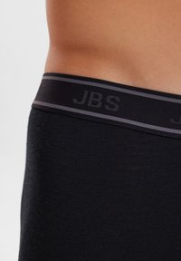 Black boxer brief featuring a wide, elastic waistband with grey stripes and "JBS" embossed text. Smooth fabric texture, close-up view.