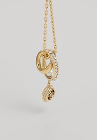 Gouden hanger ketting met in elkaar grijpende ringen, waarvan er één is versierd met heldere kristallen, en een lagere bedel met een gemarmerd middenstuk. Schakel ontwerp.