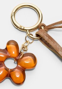 Amber blomstret nøglering med gylden metalring og brun læderrem. Har en blank finish og et centralt hul til fastgørelse.