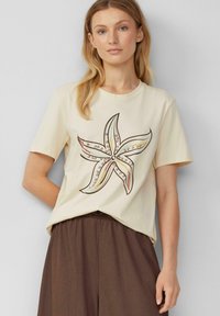 Cream-colored cotton t-shirt featuring a starfish graphic in brown with colorful accents, relaxed fit, round neckline, short sleeves.
