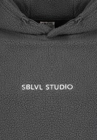 Gray fleece pullover with a textured surface, featuring a half-zip collar and the embroidered text "SBLVL STUDIO" in white.