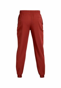 Rote Sporthosen mit elastischem Bund, schmal zulaufenden Beinen, Seitentaschen und einer einzelnen Gesäßtasche, aus glattem, leichtem Stoff.