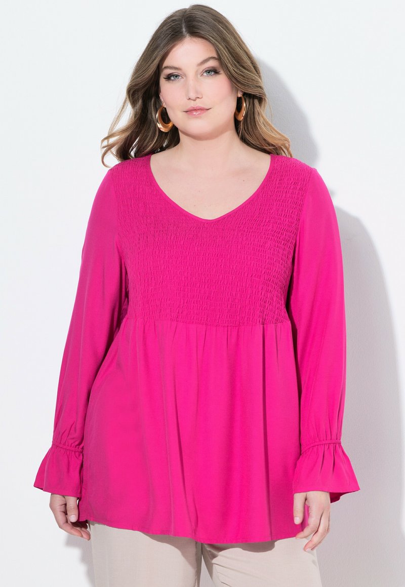 Top fucsia a maniche lunghe con corpino arricciato, scollo a V e maniche a campana, caratterizzato da una silhouette fluida e una tekstura morbida.
