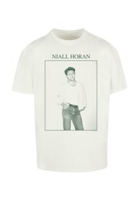 Hvit bomulls t-skjorte med et grønt grafisk trykk av en mann i en ramme, med teksten "NIALL HORAN" over bildet. Casual passform.