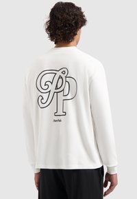 Weißes Langarmshirt mit auffälligem schwarzem Grafiklogo auf dem Rücken, aus glattem Stoff gefertigt. Einfaches Design mit lockerer Passform.