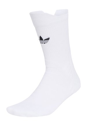 Witte crew-sok met geribbelde textuur en zwart Adidas trefoil-logo aan de zijkant, weergegeven op een voetvorm.