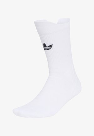 Witte crew-sok met geribbelde textuur en zwart Adidas trefoil-logo aan de zijkant, weergegeven op een voetvorm.