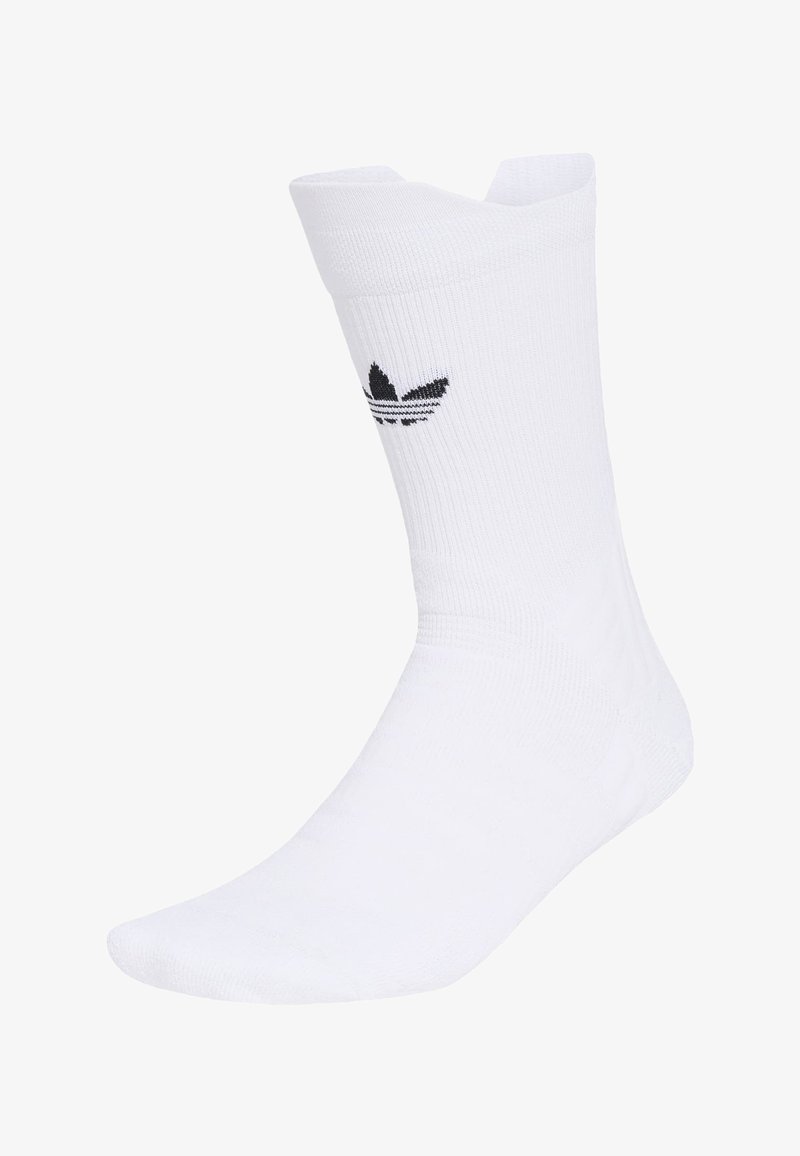 Chaussette blanche mi-mollet avec texture côtelée et logo trefoil noir Adidas sur le côté, présentée sur une forme en forme de pied.