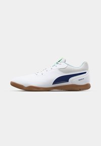 White athletic shoes with a textured mesh upper, navy accents, a gum rubber sole, and lace-up closure. Features "TRUCO III" branding.