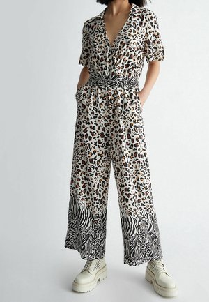 Jumpsuit mit Leopardenmuster, kurzen Ärmeln, tiefem V-Ausschnitt, tailliertem Schnitt, seitlichen Taschen und einem zebraartigen Akzent am Saum.