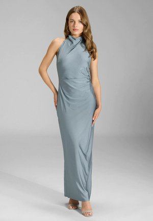 Długa, bezrękawnikowa sukienka wieczorowa z miękkiego niebieskiego materiału. Posiada wysoki dekolt i drapowany fason. Długość do ziemi, gładka tekstura. Srebrne sandały.