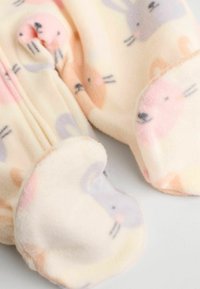 Flauschiger, cremfarbener Baby-Overall mit pastellfarbenen Hasenmuster in Rosa, Grau und Orange; verfügt über weiche Bündchen und einen Reißverschluss.