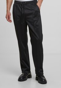 Sorte jog pants med en elastisk talje med snøre, der har en glat tekstur, sidesømme og en tapered design.