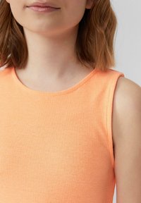 Ärmelloses orangefarbenes Rippenshirt mit rundem Ausschnitt, aus einem weichen Stoff gefertigt. Die Textur ist leicht strukturiert mit vertikalen Linien.