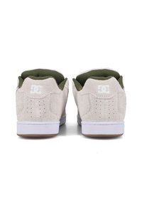 Jasnoszare zamszowe sneakersy z białą podeszwą i zielonym wnętrzem, z perforowanymi detalami i logo DC na zapiętku.