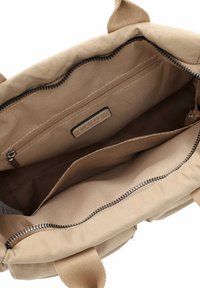 Beige Stoffhandtaschen-Innenraum mit Reißverschlusstasche, offenem Fach und eingenähtem Markenetikett "SURI FREY".