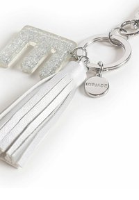 Portachiavi in acrilico trasparente con logo in glitter argento texturizzato, nappina in pelle bianca e hardware in metallo argentato, caratterizzato da un tag circolare con la scritta "MIRIAD" incisa.