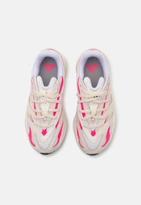 Zapatillas deportivas beige con acentos en rosa, paneles de malla y una superficie texturizada. Cuentan con un cuello acolchado y cordones para un ajuste seguro.