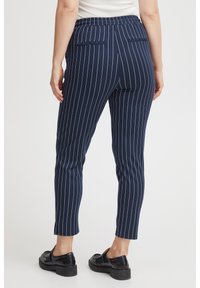 Navy blue, vertical striped trousers with a stretchy waistband, featuring two back pockets and a tapered leg design. Smooth fabric texture.