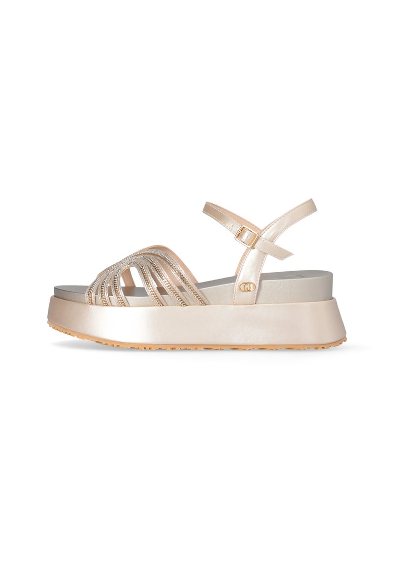 Sandaña de plataforma con tiras metálicas en color oro rosa, hebilla ajustable en el tobillo, suela plana y suela de goma texturizada para un mejor agarre.